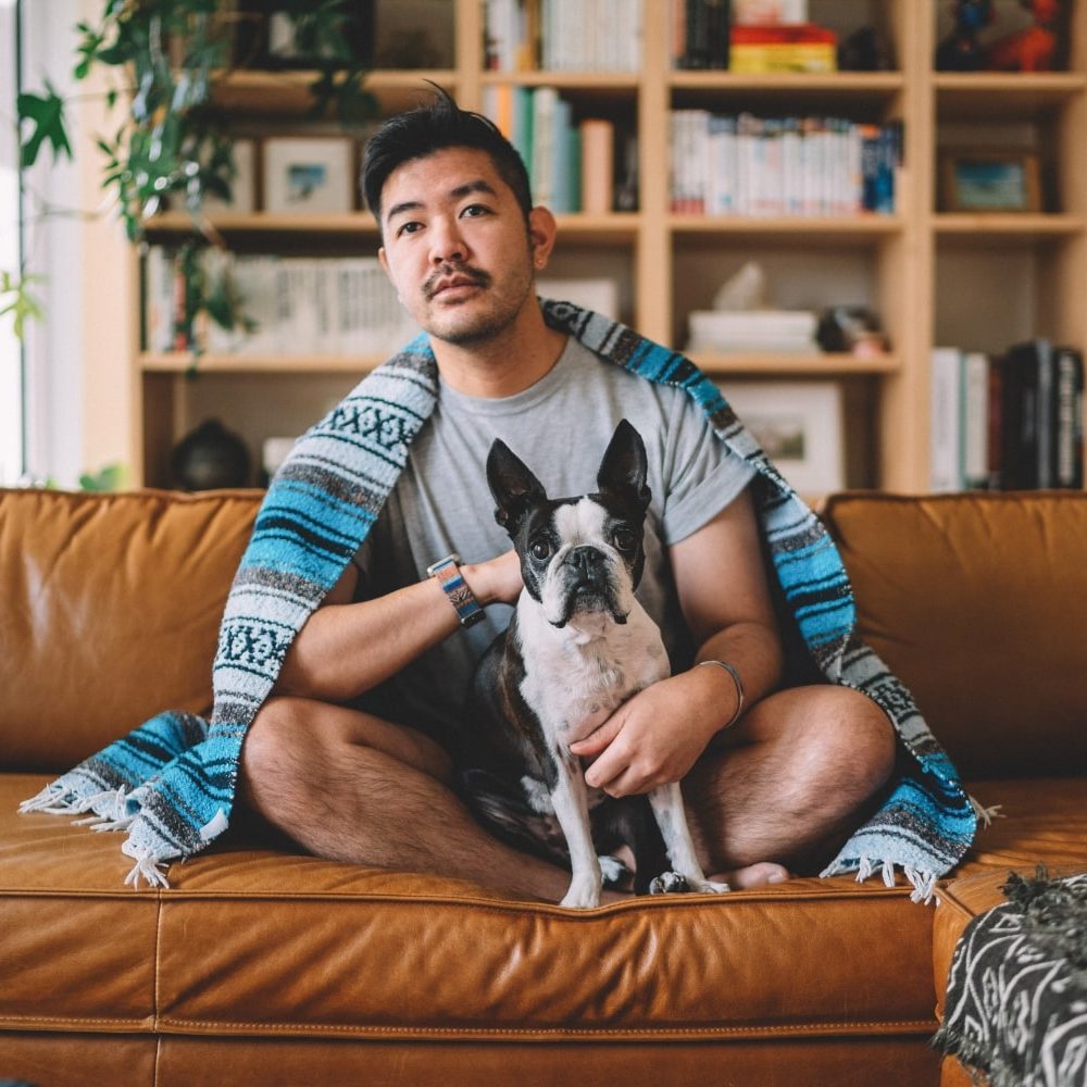 guy-sitting-on-couch-lounging-with-his-dog-watchi-2023-11-27-05-13-08-utc-min